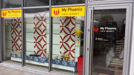 Schaufenster und Eingang eines Asia-Supermarkts "My Phoenix" mit rotem Design und Dekorationen.