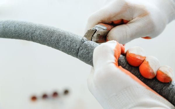 Eine Person passt die installierte Rohrdämmung an die Wasserleitung an.