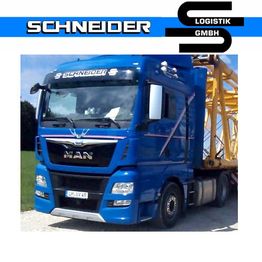 Blauer MAN-Lkw der Schneider Logistik GmbH auf einer Landstraße, beladen mit gelbem Kran.