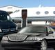 Private jet on tarmac with a black limousine and van in the foreground.