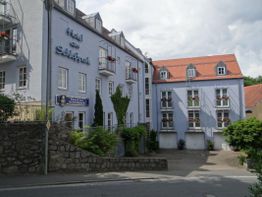 Mehrstöckiges Hotel mit blauer Fassade und roten Dächern bei bewölktem Himmel.