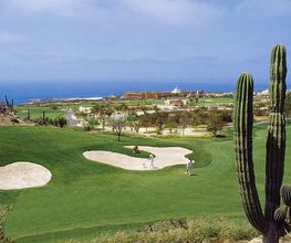 Campo de golf con cactus y vista al mar. Personas jugando al fondo bajo un cielo azul.