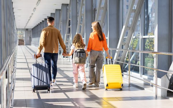 Eine Familie ist unterwegs in den Urlaub. Sie laufen durch einen Gang an einem Flughafen.