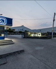 Edificio de la empresa KSB con logotipo iluminado en la entrada y un cielo despejado al atardecer.