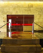 Piscina interior moderna con escalera y pared de piedra. Ambiente relajante y elegante.