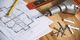 Blueprint, drill, screws, and tools on wooden table for construction project.