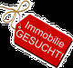 Rotes Schild mit der Aufschrift "Immobilie GESUCHT!" und angehängter Schnur.