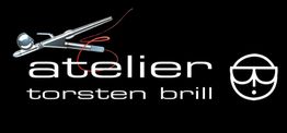 Logo von Atelier Torsten Brill mit Schere, rotem Faden und stilisiertem Gesicht auf schwarzem Hintergrund.