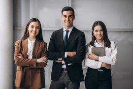 Tres personas sonriendo con brazos cruzados, dos mujeres y un hombre en ropa formal.