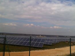 Solaranlage auf einem Feld an einem bewölkten Tag, umgeben von einem Zaun.