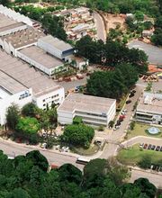 Vista aérea de um complexo industrial cercado por vegetação e áreas residenciais.