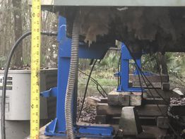 Yellow measuring tape by blue supports under a raised structure with wooden blocks.