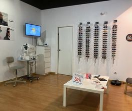 Tienda de gafas con descuento del 50%, paredes blancas y mobiliario moderno.