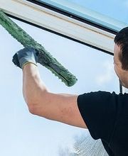 Person reinigt ein Fenster mit einem Schwamm; Text über Gebäudewartung in der Region Luzern.