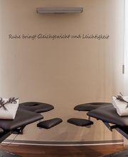 Zwei Massageliegen in modernem Raum mit beruhigender Dekoration und Schriftzug an der Wand.