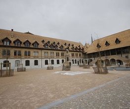 Großer gepflasterter Platz mit historischem Gebäude im Hintergrund unter grauem Himmel.