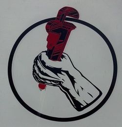 Hand holding a red pipe wrench inside a black circle.