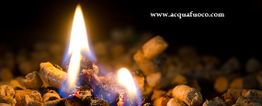 Fiamma tra pellet di legno ardente, sfondo scuro. Testo "www.acquafuoco.com" in alto a destra.