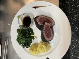 Teller mit Sesam-Thunfisch, Spinat, Kartoffelpüree und Sojasoße.