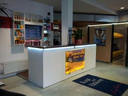 Empfangsbereich eines Sonnenstudios mit Prospekten, Postern und dekorativer Beleuchtung.