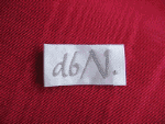 Etikett mit handgeschriebenem "d6/N" auf rotem Stoffhintergrund.