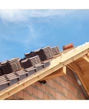 Tejado en construcción con tejas marrones y estructura de madera bajo un cielo azul.