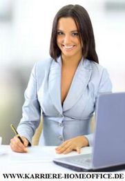 Geschäftsfrau im Anzug am Schreibtisch mit Laptop, schreibt etwas auf Papier.