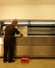 Mann bedient große, silberne Druckmaschine im Innenraum.