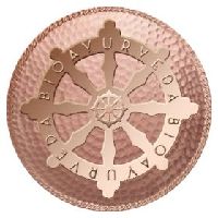 Copper wheel emblem with "BIOAVURVEDA" engraved in circular text, set against a textured background.