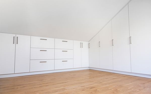 Ein weißer Schrank eingebaut unter eine Dachschräge.