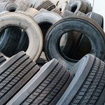 Stacked used tires in various sizes and conditions, forming a cluttered arrangement.