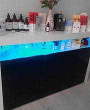 Estante de productos de belleza con iluminación azul y jarrón con flores secas encima.