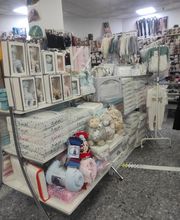 Estantería con ropa y accesorios de bebé en una tienda iluminada.