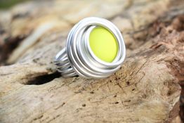 Silberner Ring mit gelbem Stein auf Holzoberfläche.