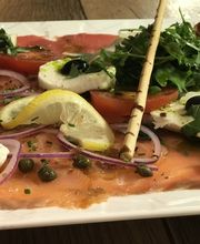 Teller mit Carpaccio, Mozzarella, Tomaten, Rucola, Zwiebeln, Kapern und Zitronenscheiben.