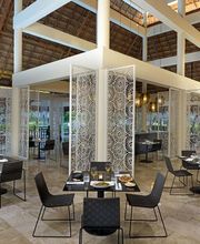 Restaurante moderno y elegante con mesas, sillas y decoración minimalista en techo de palapa.
