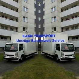 Zwei weiße Transporter vor einem Wohnhaus mit der Aufschrift "KAAN TRANSPORT Umzüge bundesweit".
