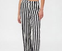 Mujer con pantalones de rayas blancas y negras, top negro y sandalias.