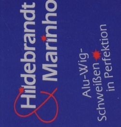 Blaues Schild mit Aufschrift „Hildebrandt & Marinho – Alu-Wig-Schweißen in Perfektion“.