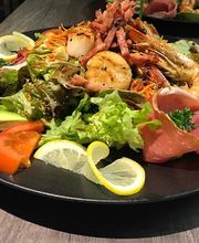 Ein Teller mit Meeresfrüchtesalat, Avocado, Tomaten, Salat und Zitronenscheiben.