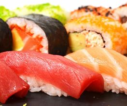 Variedad de sushi: nigiri y rollos con pescado, aguacate y arroz, en un plato.