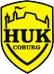 Gelbes Wappen mit schwarzer Burgsilhouette und Schriftzug "HUK Coburg".