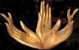 Goldene Skulptur mit vielen Händen, die nach oben zeigen, vor dunklem Hintergrund.
