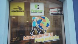 Ventana de tienda con logotipos de mensajería y paquetería: Halcourier, Redyser, Pallibox.