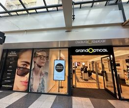 GrandOptical-winkel met brillenreclame op ramen en glazen automatische deuren.