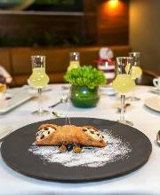 Postre sobre mesa elegante con copas y tazas, decorado con planta verde.