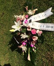 Un arreglo floral con cintas con mensajes sobre césped.