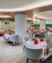 Restaurante elegante con mesas redondas, manteles a cuadros rojos, y decoración moderna.