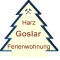 Dreieck mit Tanne, Text: "Harz Goslar Ferienwohnung" in verschiedenen Farben.