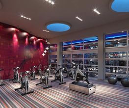 Gimnasio moderno con bicicletas de spinning y decoración colorida en la pared y el suelo.